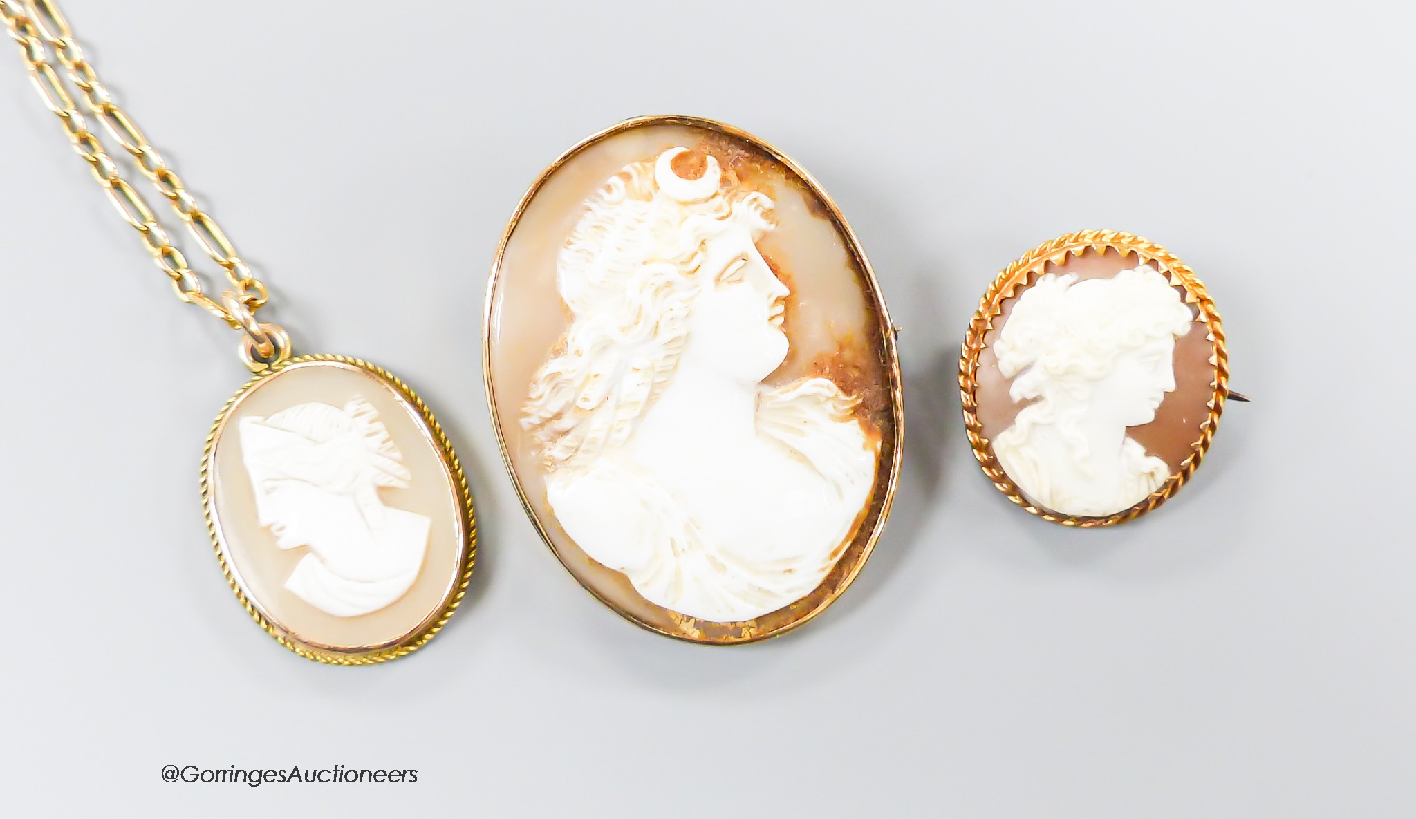 A 9ct gold mounted cameo shell pendant, 21mm, on a 9kt chain, gross 6.1 grams and two cameo shell brooches